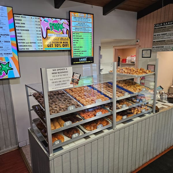 A Dank Donuts display case filled with various donuts, donut holes, and pastries.