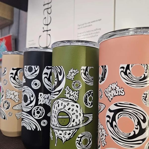 Four Dank Donuts tumblers in beige, black, olive, and peach, featuring donut-themed designs.