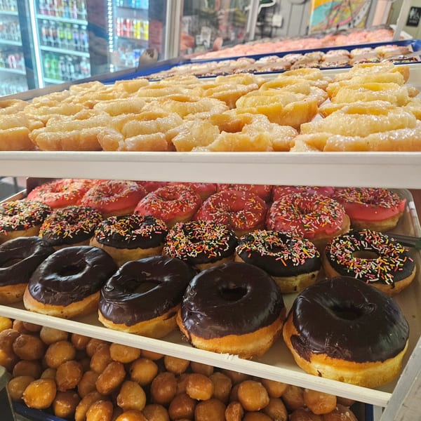 A display case filled with various Dank Donuts, including glazed, chocolate, and sprinkle-covered varieties.