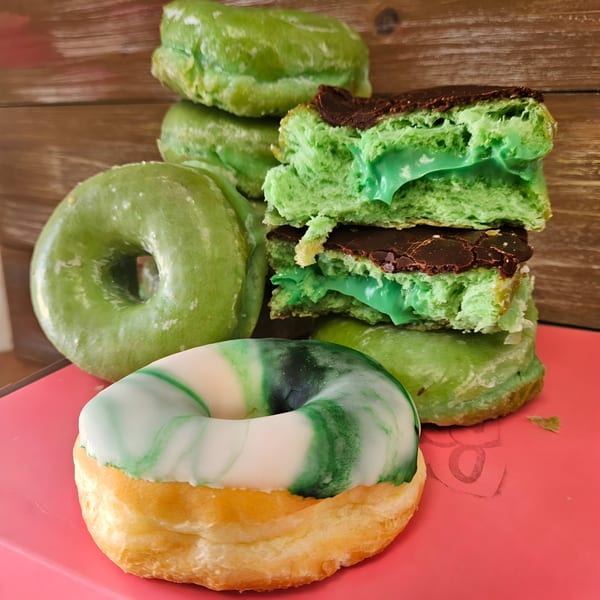 A stack of green Dank Donuts, some with chocolate and green filling, and one marbled green and white.